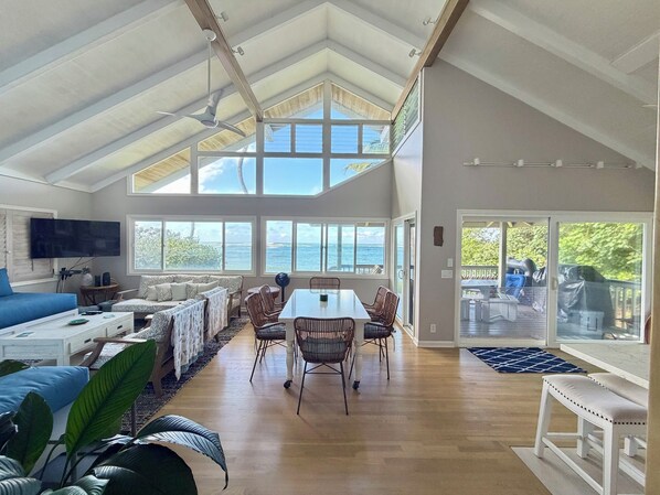 A spacious living area with a high ceiling, a dining table, and a seating arrangement.