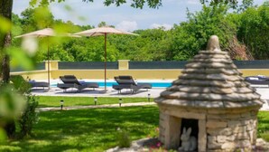 A stone gazebo in a lush garden with a pool and lounge chairs in the background. - Villa Aniva by Interhome (Rovinj/Žminj)