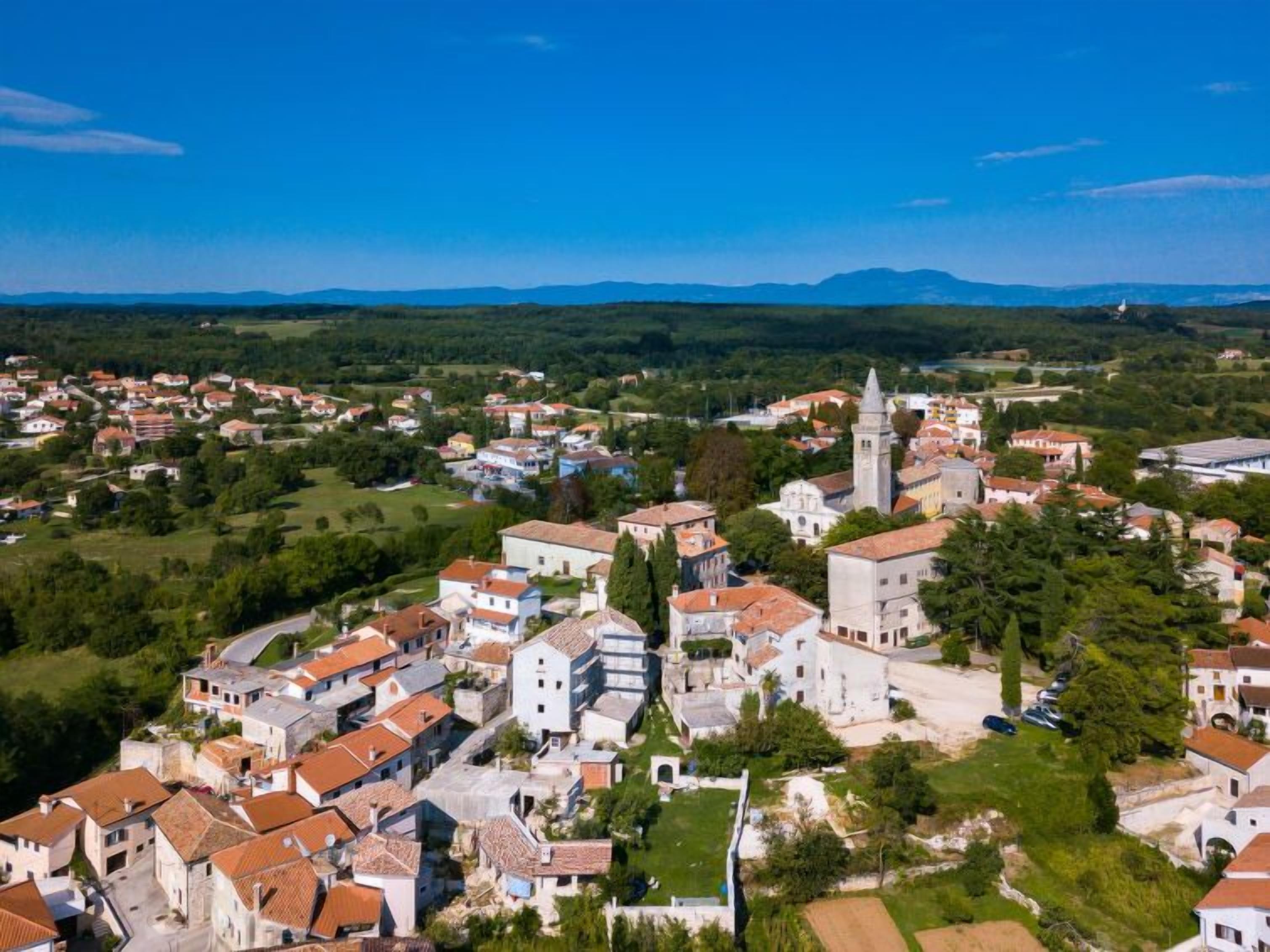 Eine Stadt mit historischen Gebäuden, einem markanten Kirchturm und umgebender Grünfläche.
