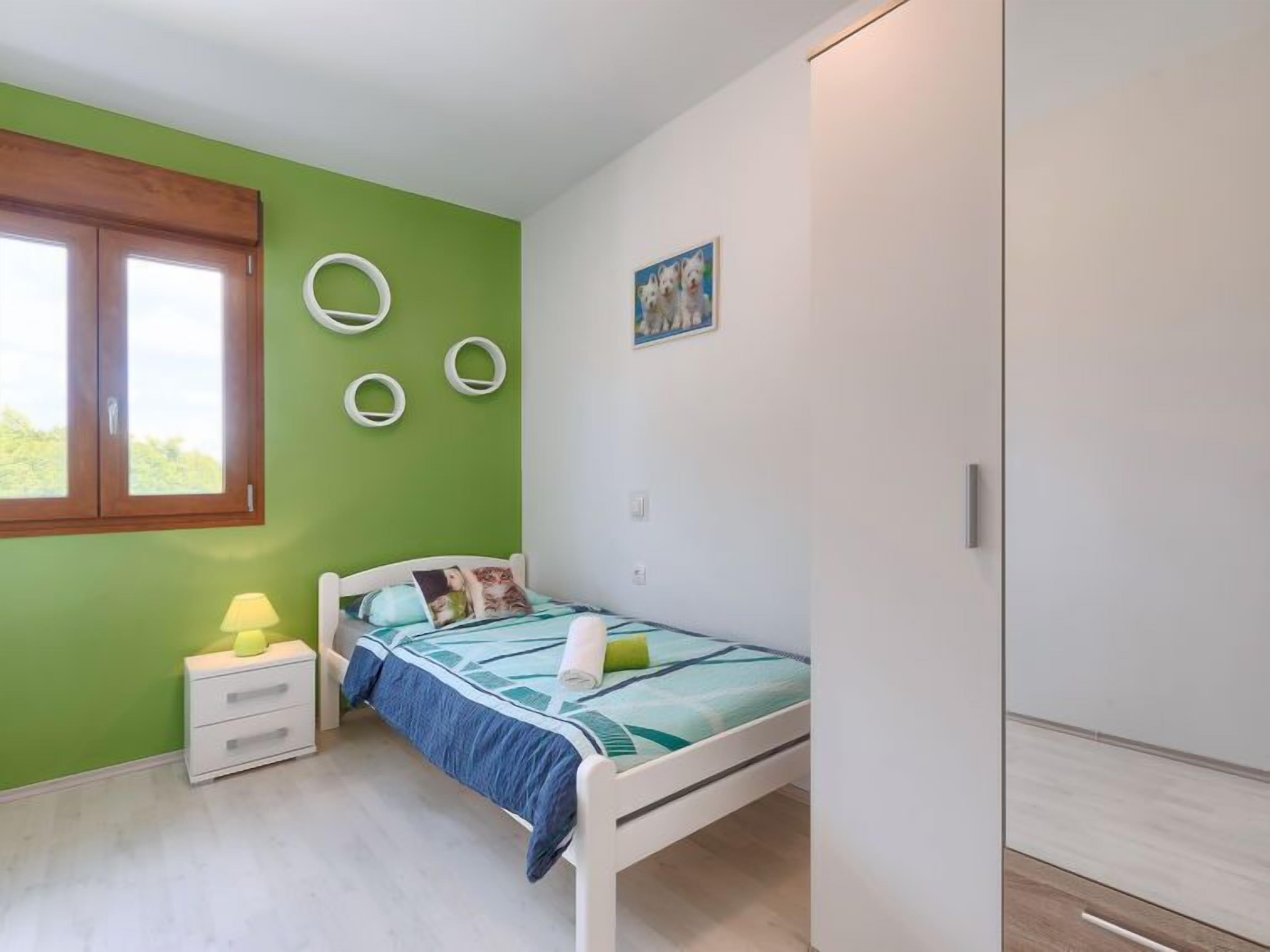 Une chambre à coucher avec un lit, une table de chevet, une lampe, une armoire et une fenêtre.