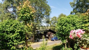 Eine rustikale Holzhütte, umgeben von üppigem Grün und blauem Himmel.