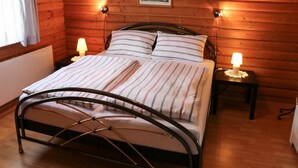 Ein Zimmer mit Holzwänden, einem Bett, zwei Nachttischlampen und einem gerahmten Bild an der Wand.