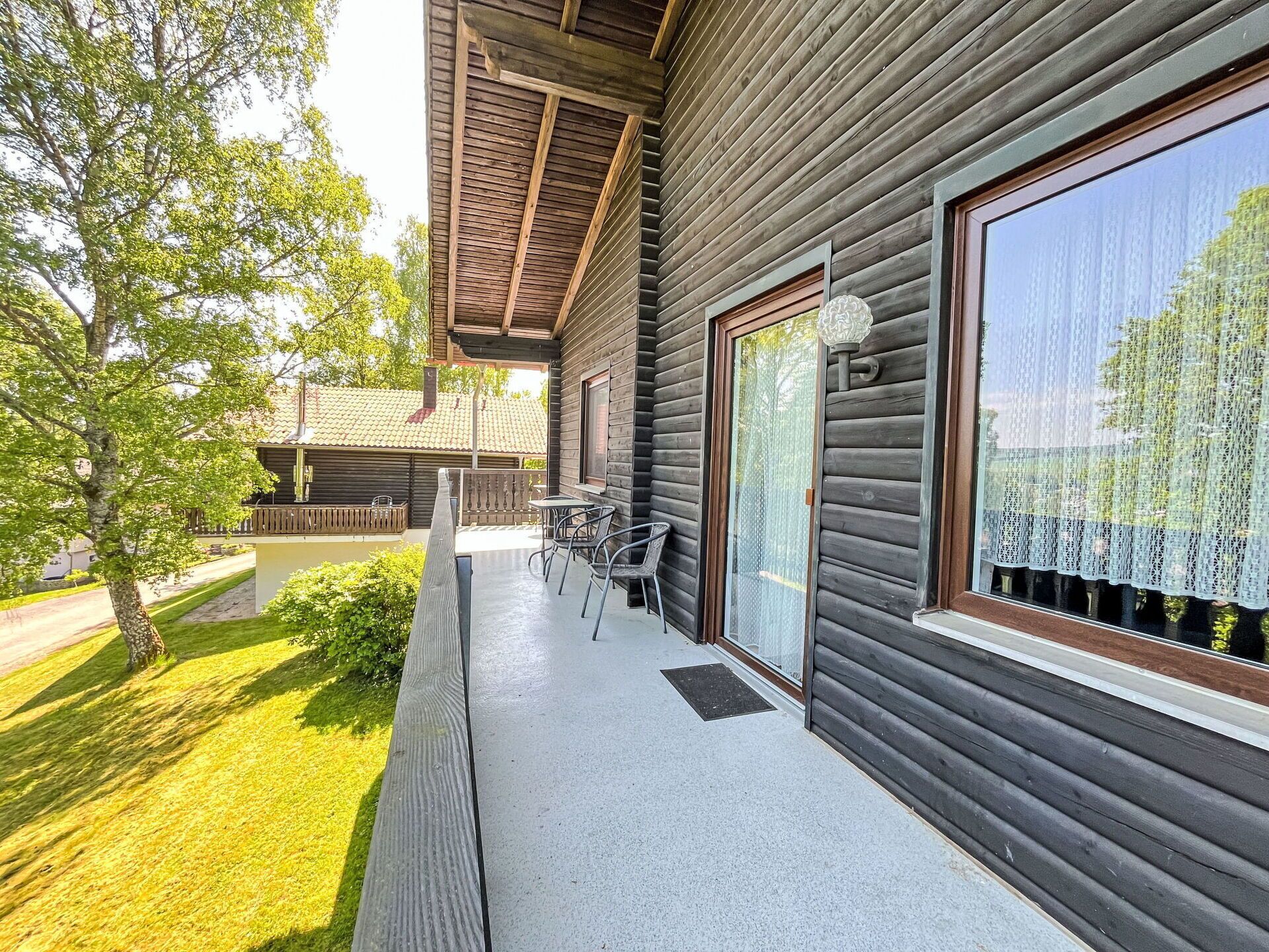A wooden cabin with a balcony, a table, and chairs.