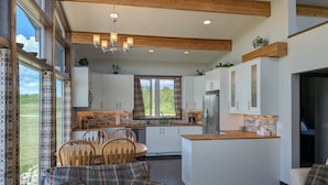 Une cuisine moderne avec des meubles blancs, un îlot central et un coin repas doté de chaises en bois.