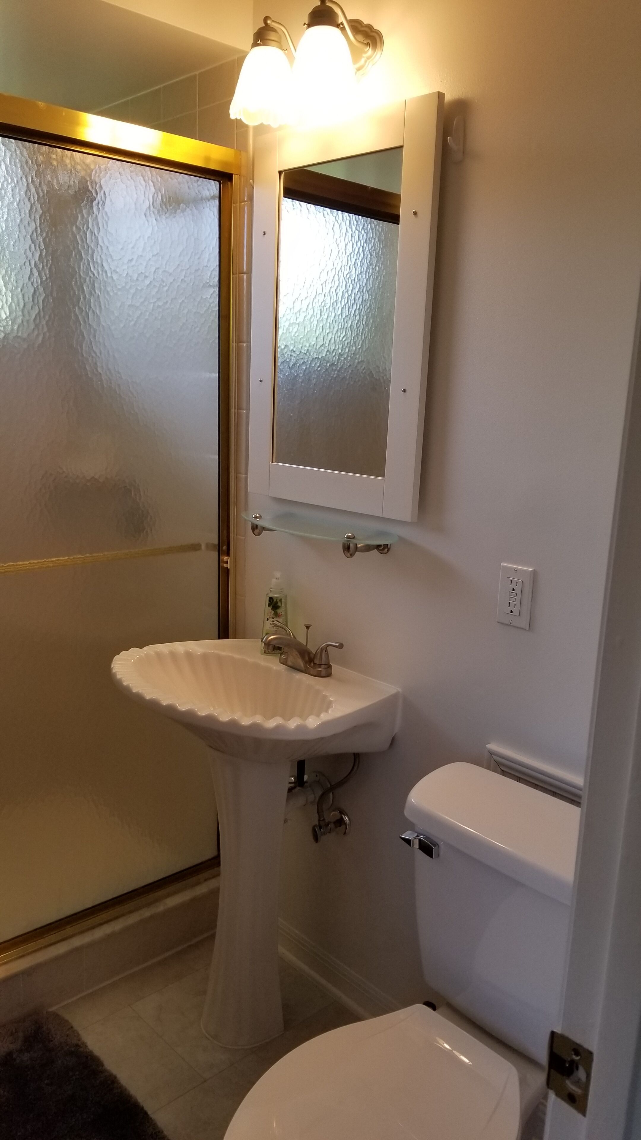 A bathroom with a white sink, a toilet, and a frosted glass shower door.