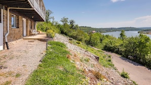 A stone building with a balcony, a gravel path, and a view of a lake.