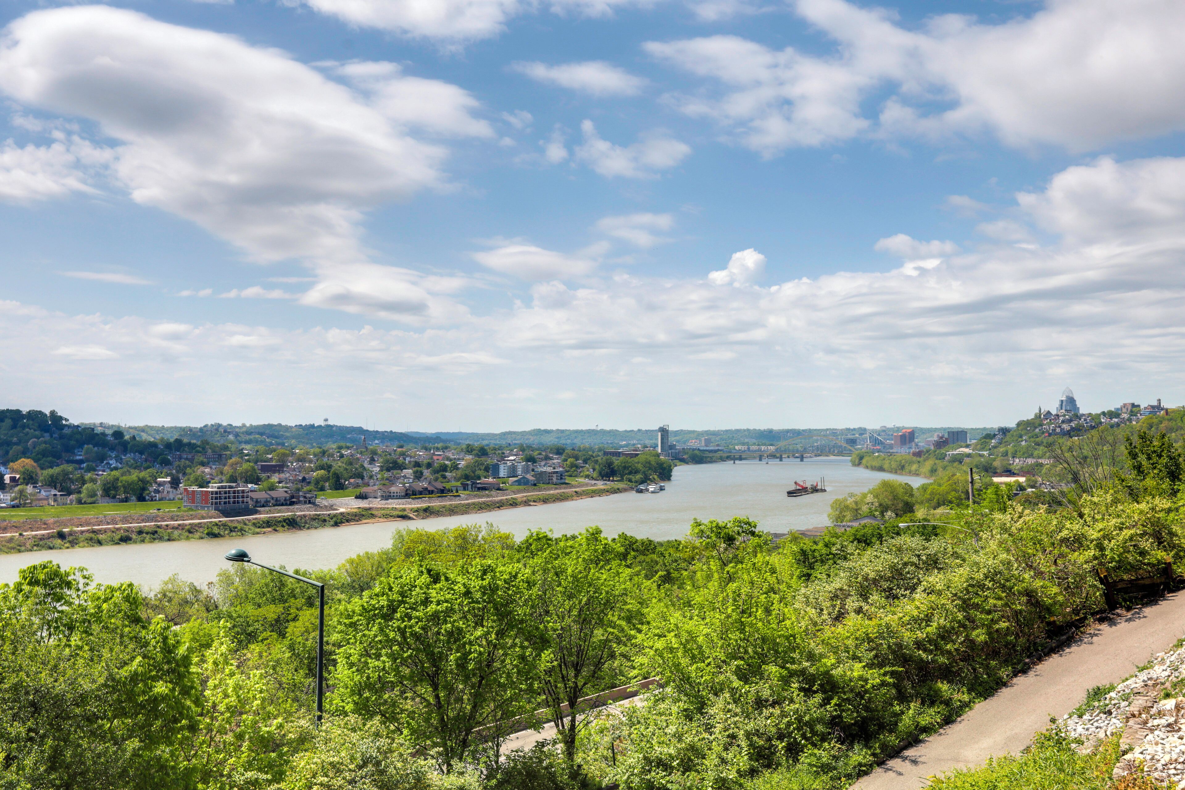 A river with a bridge, greenery, and buildings in the background.