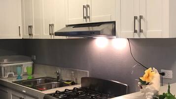 A modern kitchen with white cabinets, a stainless steel stove, and a countertop.