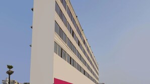 A multi-story building with a modern design, featuring a prominent white facade and a pink accent. - Hotel Mani International (Patna)