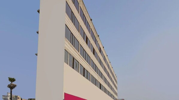 A multi-story building with a modern design, featuring a prominent white facade and a pink accent. - Hotel Mani International (Patna)