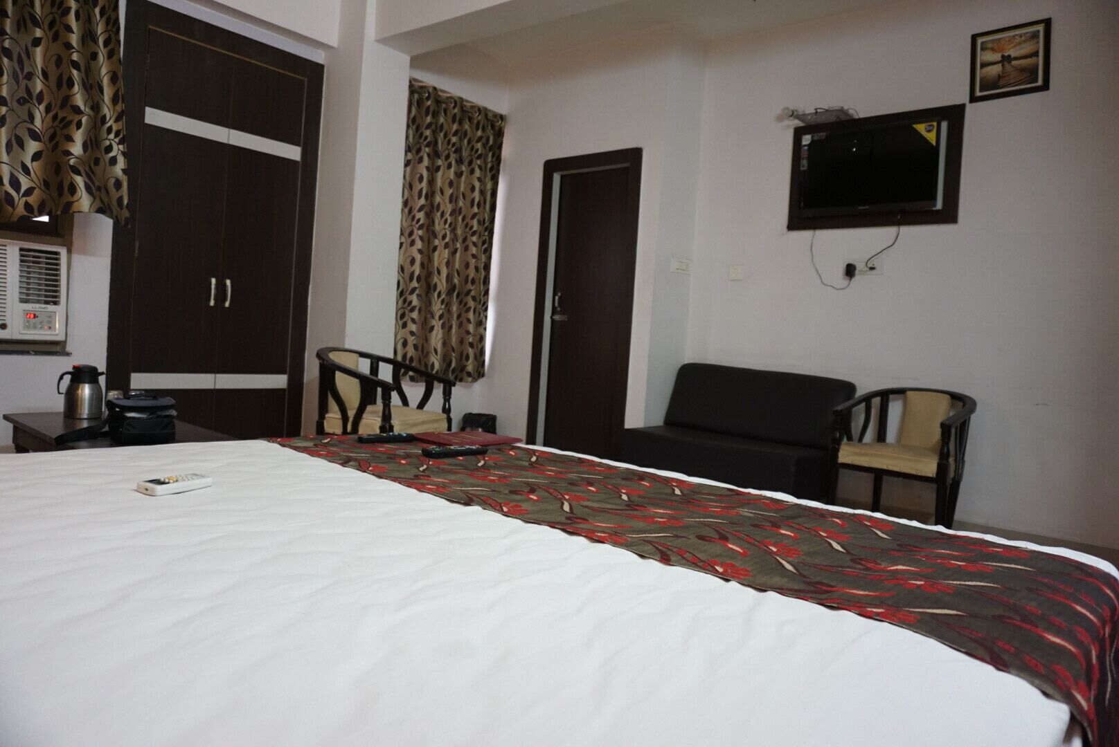 Habitación de hotel con cama, dos sillas, televisor y armario.