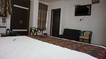 Habitación de hotel con cama, dos sillas, televisor y armario.