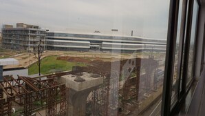 A modern building with a glass facade, surrounded by construction sites and scaffolding. - Hotel Mani International (Patna)