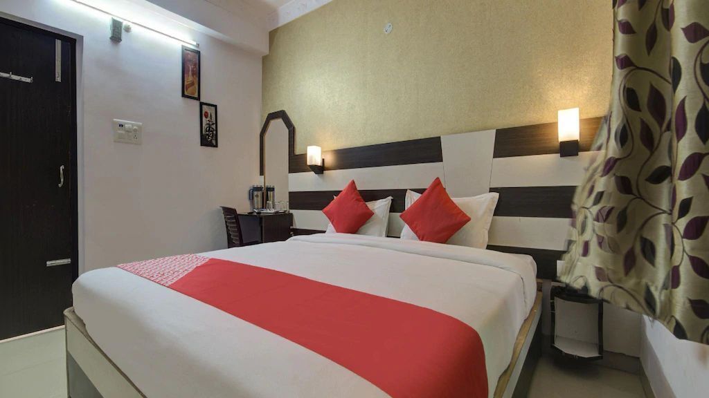 A hotel room with a large bed, a nightstand, a lamp, and a curtain.
