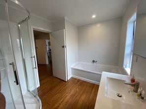 Un baño con cabina de ducha de vidrio, bañera y lavabo con espejo.