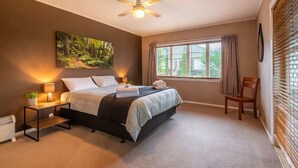 Un dormitorio con cama, mesita de noche, lámpara y ventilador de techo.