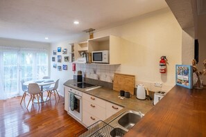 Una cocina moderna con comedor, piso de madera y ventana con cortinas.