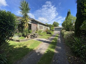 Un sendero que lleva a una casa con jardín y cielo despejado.