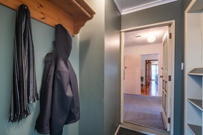 En hall med en klädhängare, en dörr som leder till ett annat rum och en lampa.