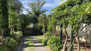Un estrecho sendero bordeado por abundante vegetación y una valla de madera.