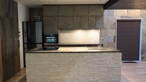 A modern kitchen with a stone island, built-in oven, and a sleek faucet. - Pres De La Mer (Hakodate)