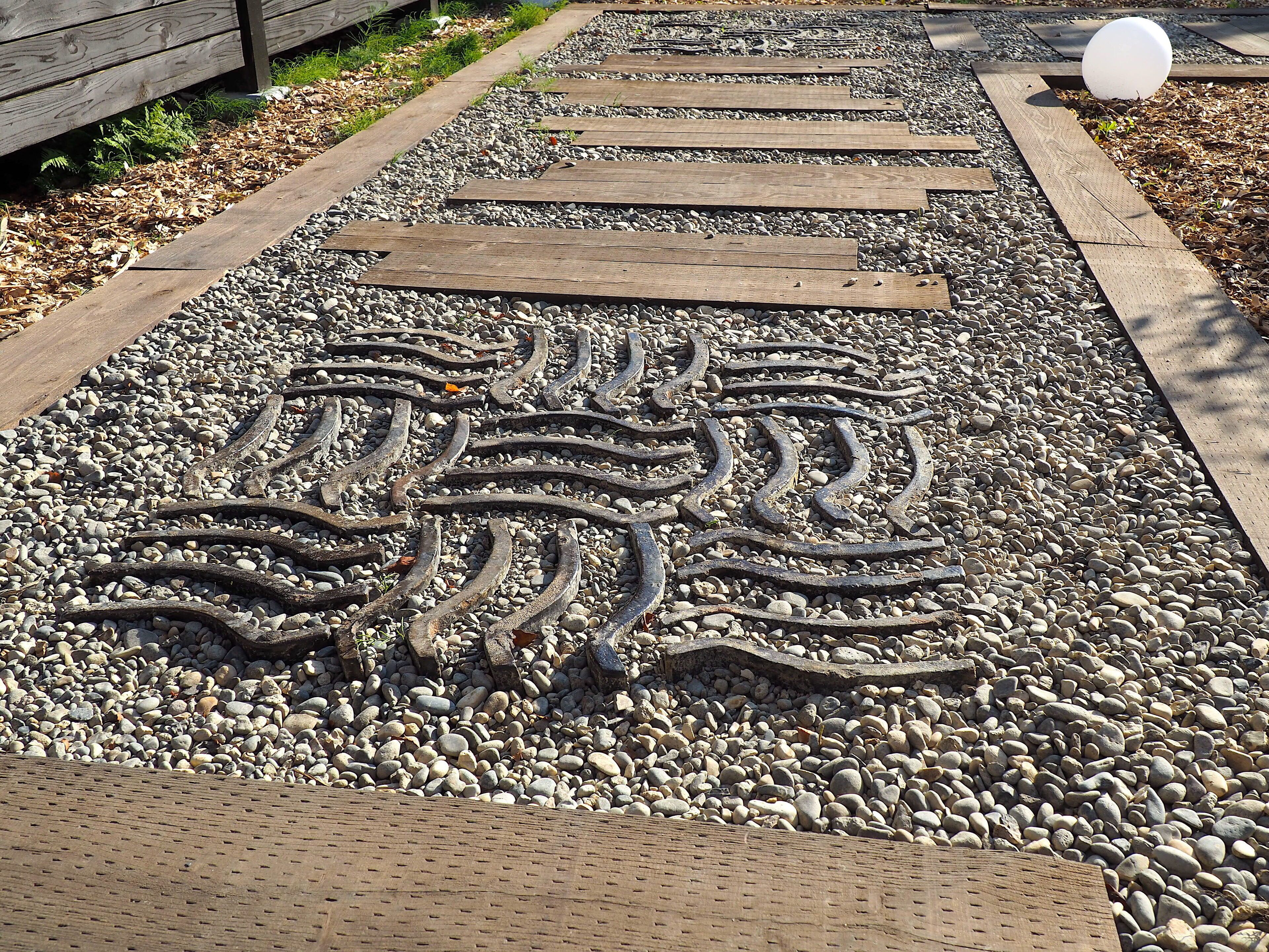 A pathway with wooden planks and a decorative metal pattern.