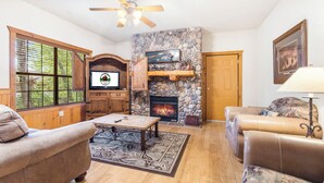 Una sala de estar acogedora con chimenea de piedra, muebles de madera y un televisor.