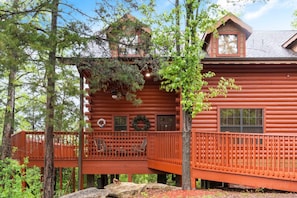 A log cabin with a wooden deck, two windows, and a door.