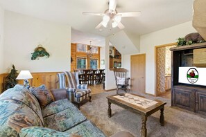 A living room with a sofa, armchairs, a coffee table, a chandelier, and a television. - Rustic, Spacious Cedar Log Cabin near Branson's Famous 76 Strip! (Branson)
