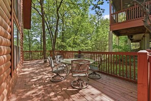 A wooden deck with outdoor furniture, a glass table, and a red railing. - Rustic, Spacious Cedar Log Cabin near Branson's Famous 76 Strip! (Branson)