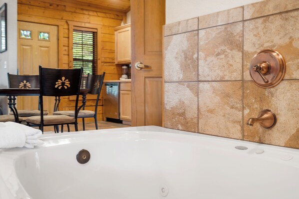 A bathroom with a bathtub, a wooden door, and a tiled wall.