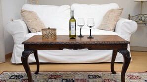 Une table en bois avec une bouteille et deux verres posés sur un tapis à motifs.