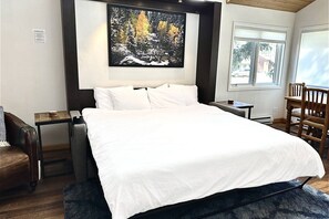 A bedroom with a large bed, a nightstand, a chair, a desk, and a painting on the wall. - Steps to Ski/Town Bus/Pool/HotTub/Grill-2 Levels (Steamboat Springs)
