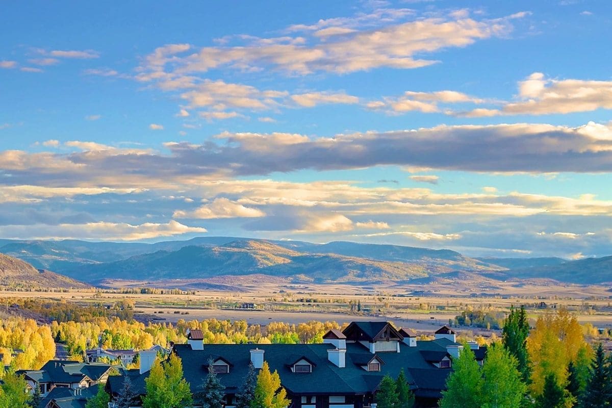 A residential area with houses, a clear sky, and distant mountains.