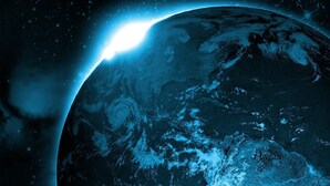 Un planeta con una luna grande en primer plano, un cielo estrellado y una fuente de luz brillante en el horizonte.