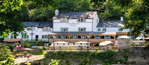 Un edificio blanco tradicional con un letrero que dice "Ye Olde Ferrie Inn" y una terraza de madera con sombrillas.