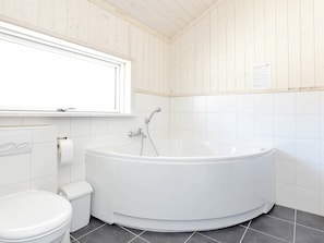Une salle de bain moderne avec une baignoire sur pieds, des toilettes et une fenêtre au-dessus du lavabo.