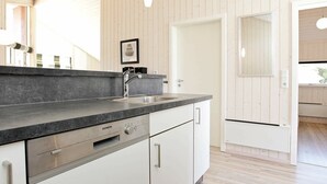 A modern kitchen with a granite countertop, stainless steel appliances, and white cabinetry. - Holiday Home in Großenbrode (Grossenbrode)
