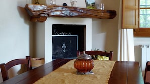 A dining room with a wooden table, chairs, a decorative vase, and a fireplace. - Holiday Home in Montecarelli With Pool (Barberino di Mugello)