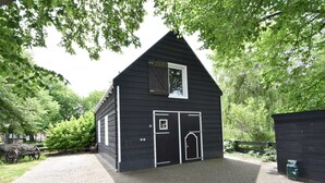A black wooden building with a gabled roof, a small window, and two doors. - Modern Holiday Home in Wolphaartsdijk With Private Garden (Wolphaartsdijk)