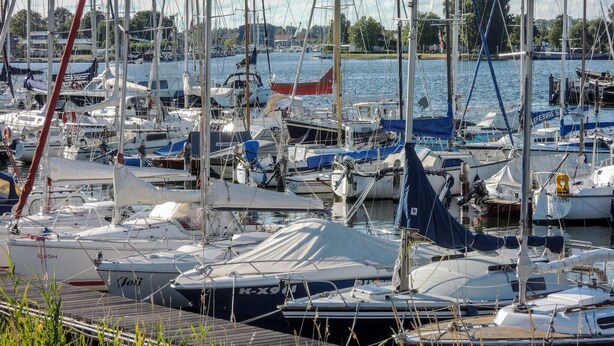 A marina with various boats docked, including sailboats and motorboats, with a wooden dock in the foreground. - Modern Holiday Home in Wolphaartsdijk With Private Garden (Wolphaartsdijk)