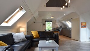 A spacious loft with a dining area, a kitchen, and a living room with a high ceiling and skylights. - Modern Holiday Home in Wolphaartsdijk With Private Garden (Wolphaartsdijk)