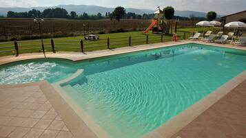 Relax by the serene pool surrounded by a well-maintained lawn and a secure fence, with a children's play area nearby.