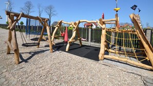 A playground with wooden climbing structures and a trampoline. - Cozy Studio 1 at the Seaside Agrotourism (Darlowo)
