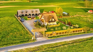 A rural property with a main house, a smaller building, and a fenced area with a thatched-roof structure. - Cozy Studio 1 at the Seaside Agrotourism (Darlowo)