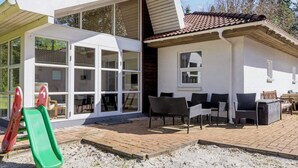 A house with a patio, outdoor seating, and a slide. - 8 Person Holiday Home in Hojslev (Hojslev)