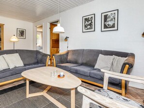 A modern living room with a grey sectional sofa, a wooden coffee table, and a patterned rug.