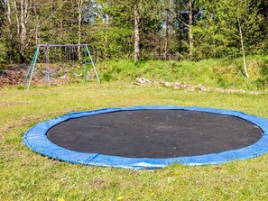 A trampoline surrounded by grass and trees.