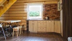 A wooden cabin kitchen with a window, wooden cabinets, a table, and stools. - Eco-friendly House by Goszcza Lake (Lubrza)
