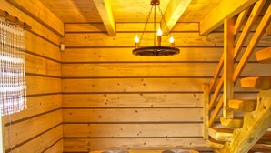 A wooden cabin interior with a dining table, chairs, a chandelier, and a staircase. - Eco-friendly House by Goszcza Lake (Lubrza)